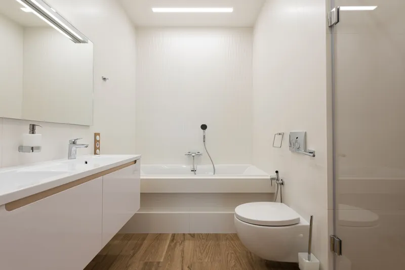 A finished bathroom with a wall-hung toilet, a bath mixer and a double basin