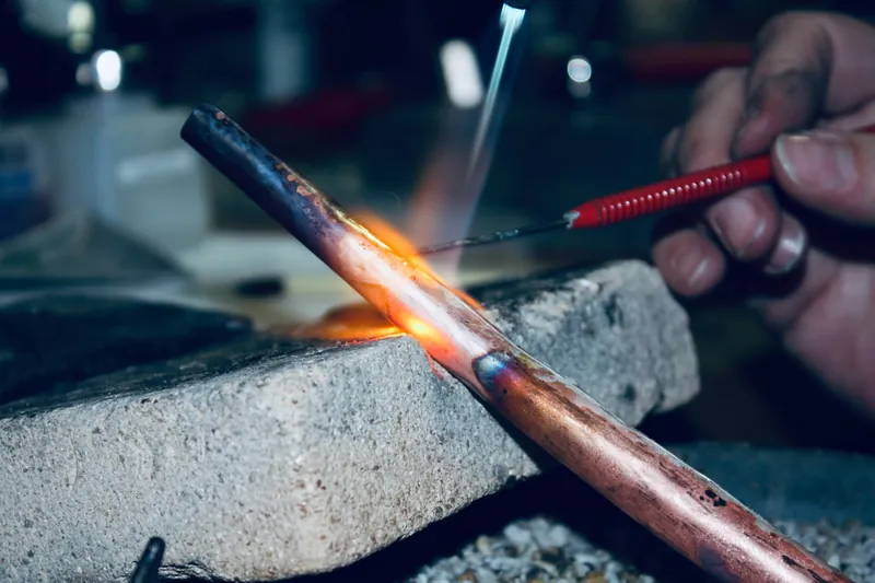 A copper pipe joint being brazed with a gas torch