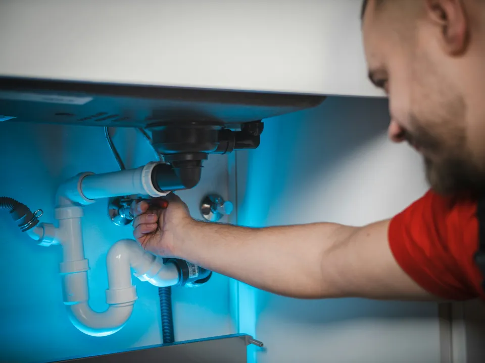 A plumber working on the copper pipes under a basin