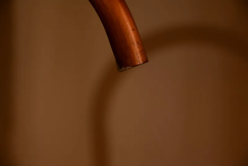 The end of a copper pipe against a warm brown background