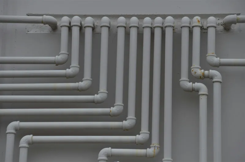Rows of white pipes running along a plant room wall