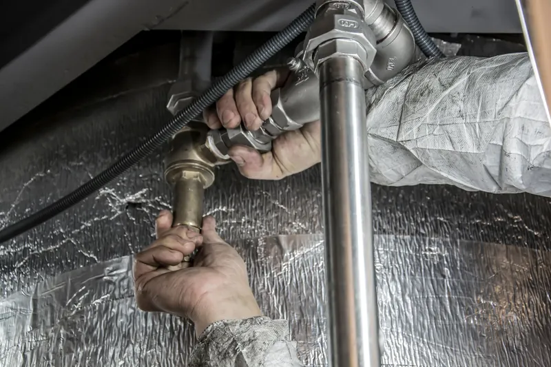 A plumber tightening a brass fitting on new steel pipework