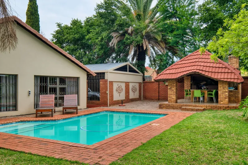 A backyard swimming pool beside a face-brick house
